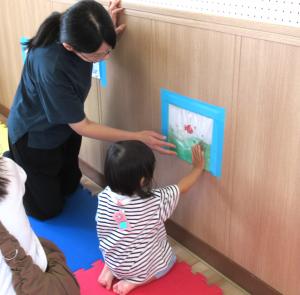 壁に貼ったウォーターマットを触る親子の画像