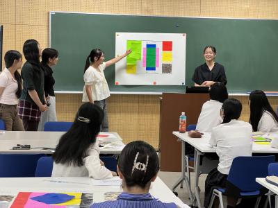 模造紙を指さしながら提案を説明する学生の画像