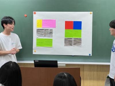 模造紙の前で提案を説明する学生の画像