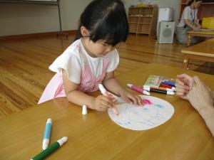 うちわに絵を描く幼児の画像