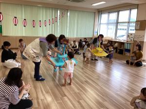 手作りの黄色や水色のおみこしをかつぐ子どもたちの画像