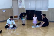 子どもが上に乗った新聞紙を保護者が引っ張っています