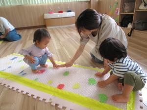 マットを触る女児と男児と母