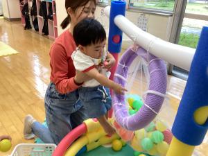 母親に抱っこされてボールを入れている様子
