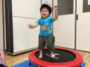 水色の服を着た子どもがトランポリンを飛んでいる様子