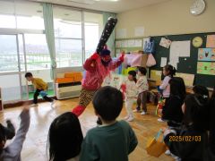 部屋で鬼に向かって豆まきをしています