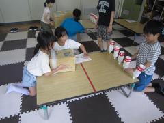 テーブルの上に並べたペットボトルでボウリングをしています