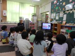 テレビ画面をたくさんの子どもが座ってみている