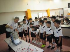 実験装置の前に並んで説明を聞く子供たち