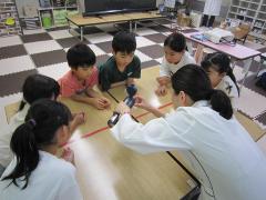 水筒からお湯を注ぐ白衣の講師とそれを見ている6人の子ども