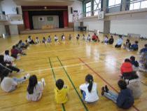 体育館で輪になり座っている子ども