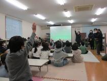 スクリーンの映像を見て挙手する子どもたち