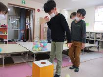 丸い穴のあいた箱の中にボールを落とす子ども