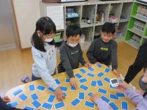 裏向きにしたトランプをめくろうとしている子ども