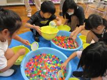 たらいに浮かべたゴムボールをすくう子供たち