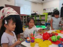 果物や野菜、お皿のおもちゃを並べて遊ぶ女の子