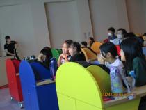 カラフルな机がたくさんあり、ポーズをとる子ども