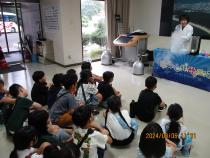 床に座って実験を見る子どもたち