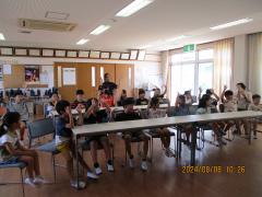 椅子に座り両手を上に上げている子どもたち