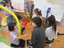 長いバルーンを手に持ち講師に教えてもらう子ども