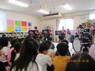 床に座る子どもたちの前で楽器を演奏している