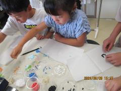 プラスチックチップを紙の上に並べる子ども