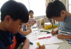 絵本を見ながら絵を描く子ども