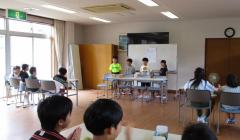 ホール前方のホワイトボード前に4人の子供が立っている