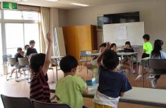 ホール後方で手を挙げて合図する子ども