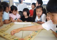 マンカラを囲んで笑顔の子どもたち