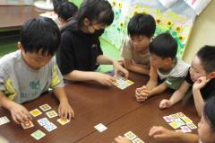 カードゲームで勝負する子どもと見守る子どもたち