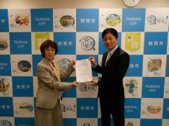 選定結果報告書を持つ委員長と市長